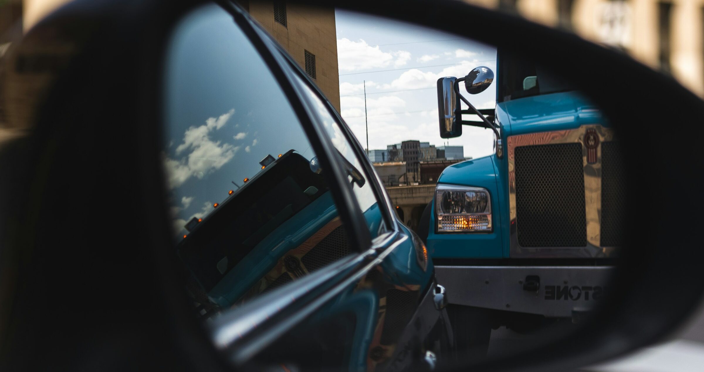 Large truck in the review mirror of a car