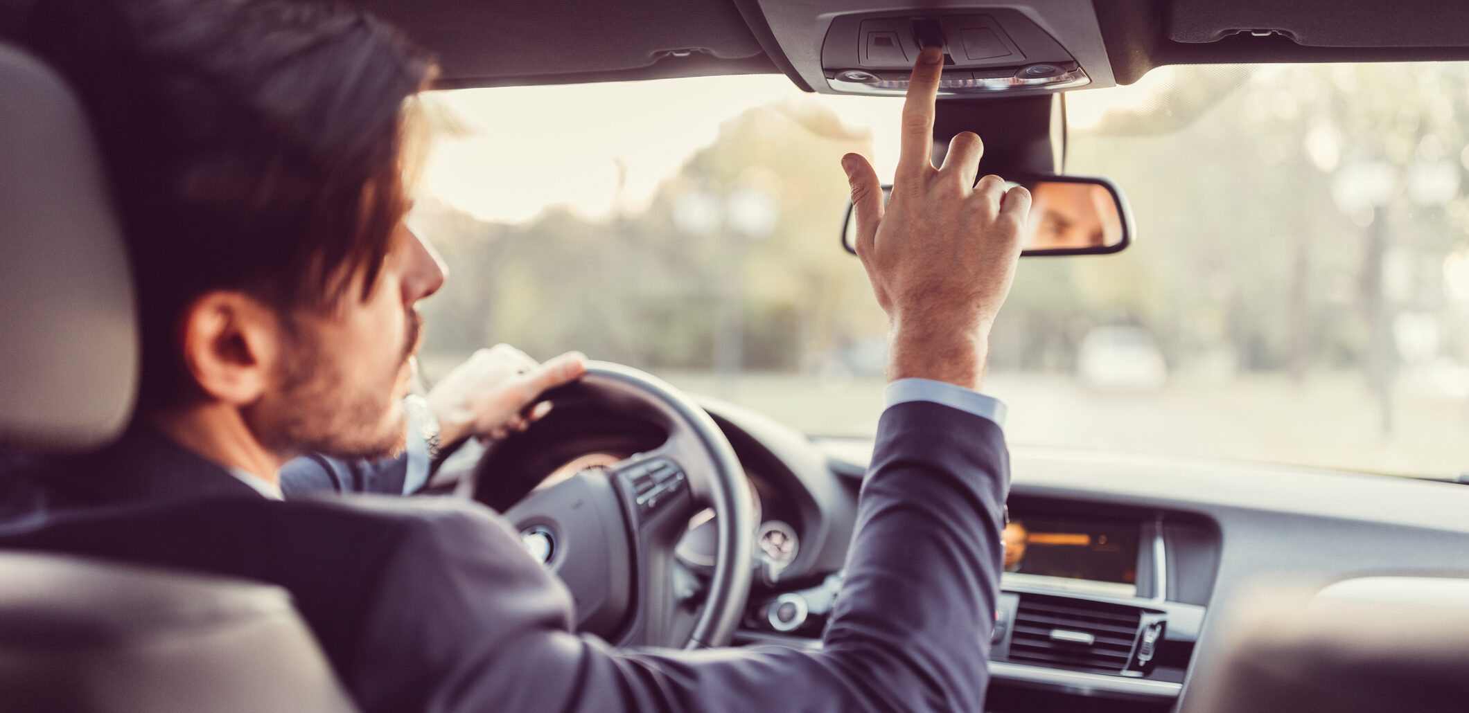Businessman traveling in car and pressing the car assistance button
