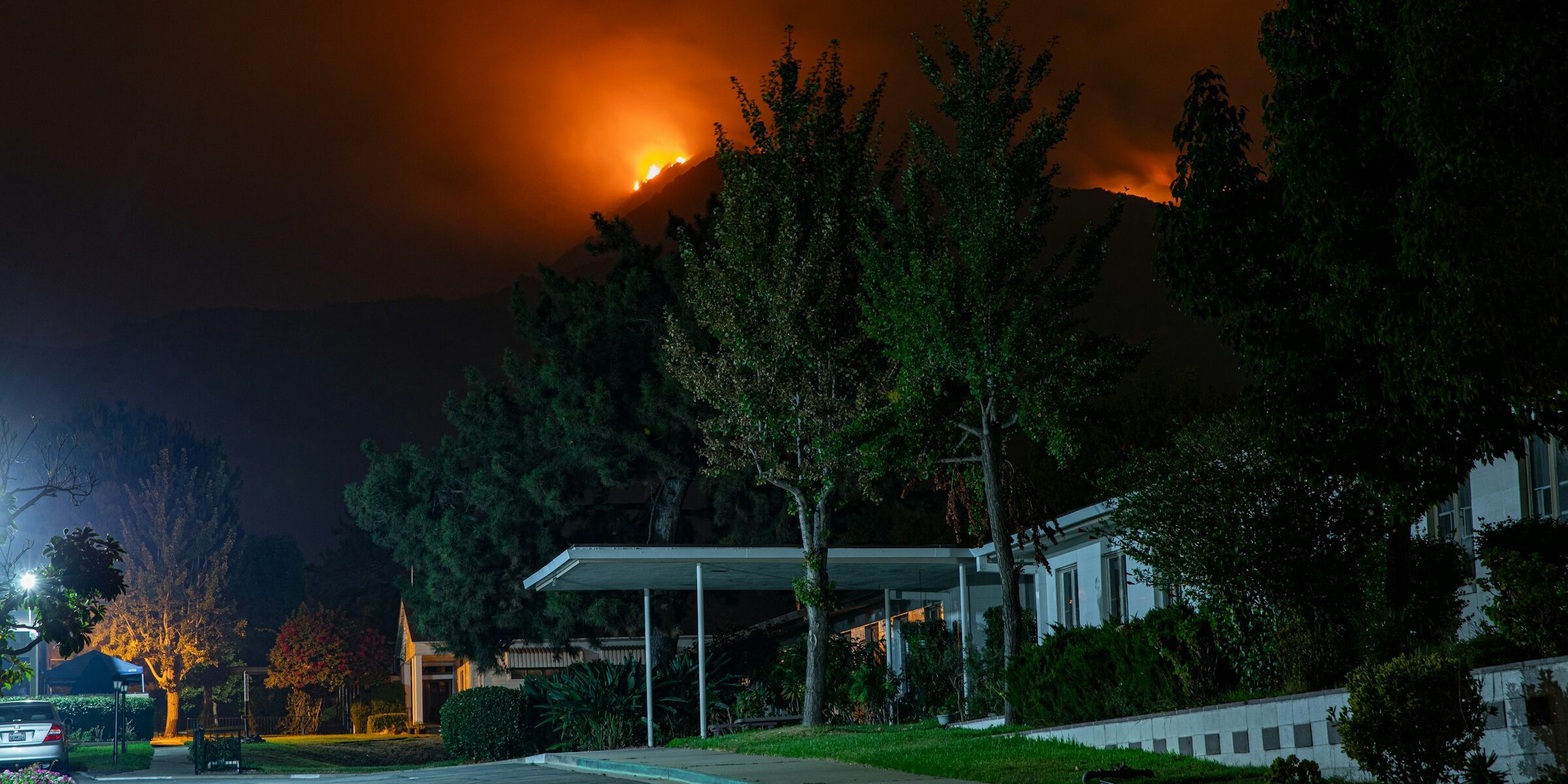 A wildfire burning on a hill above a suburban neighborhood
