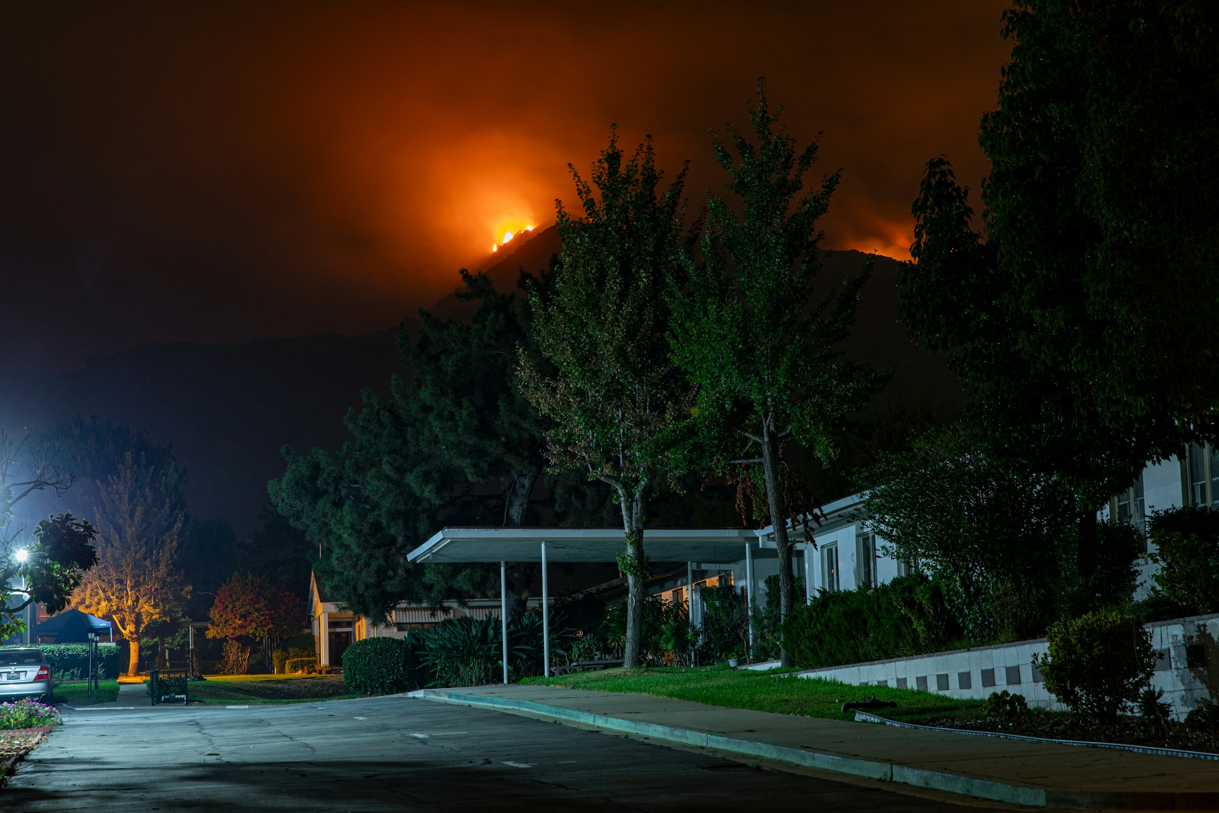 A wildfire burning on a hill above a suburban neighborhood