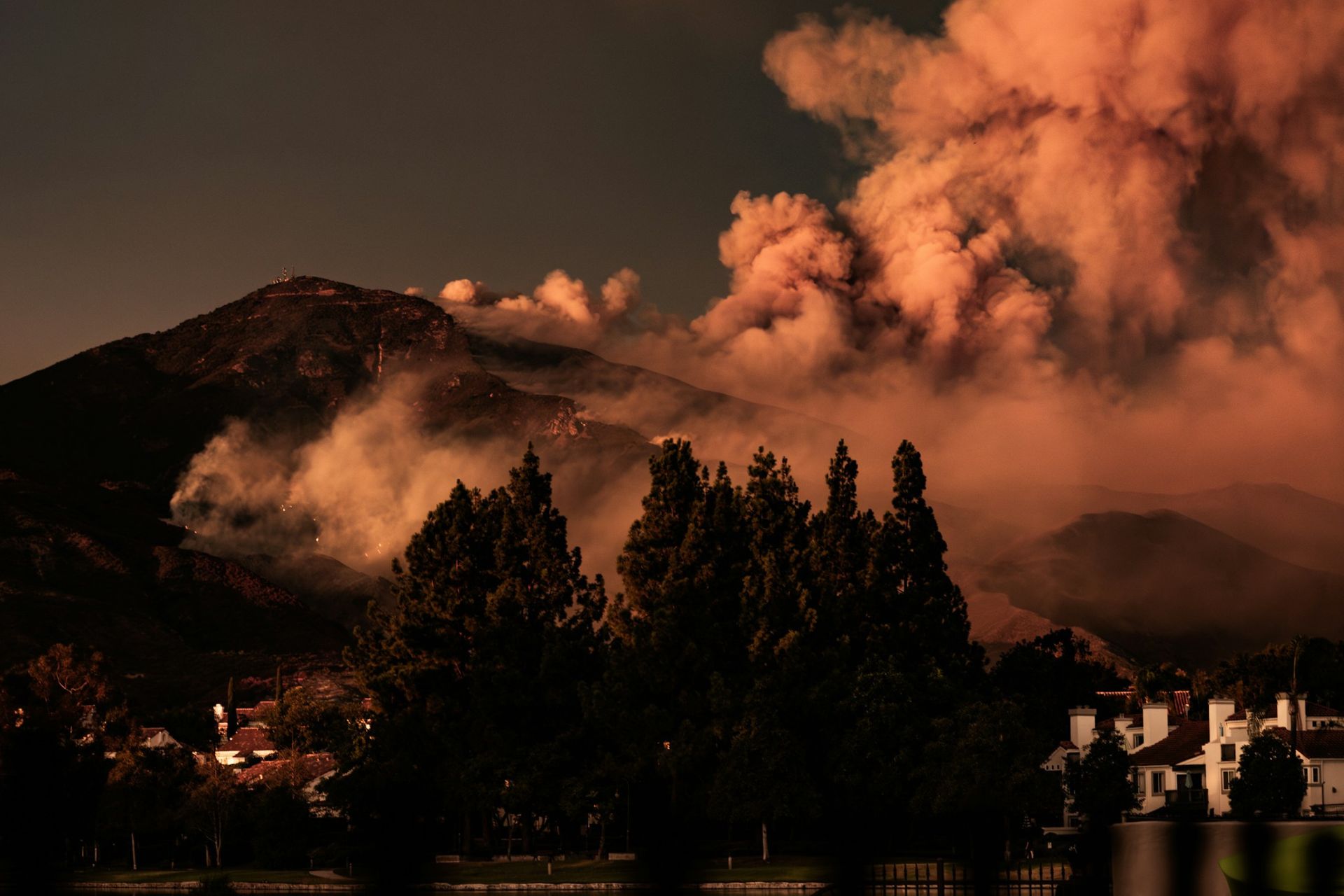 Wildfire on a mountain progressing toward homes below