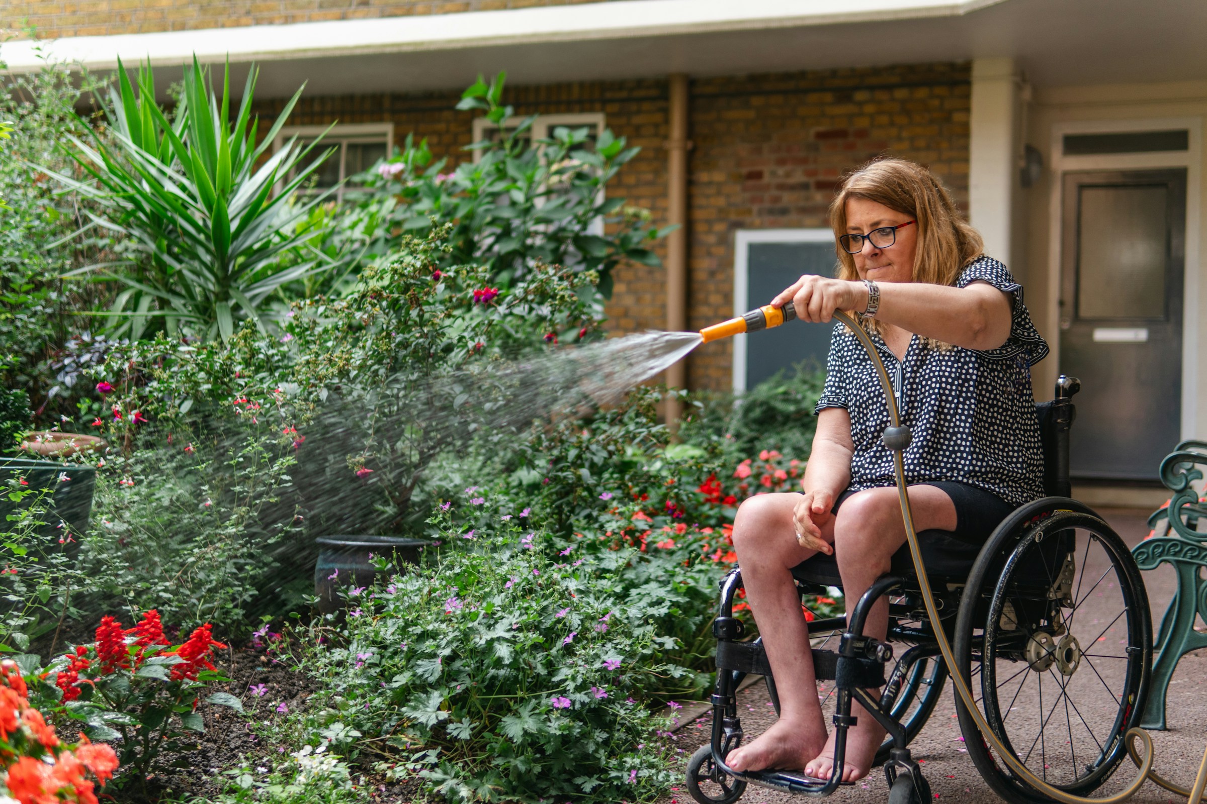 Woman in a wheelchair watering her garden