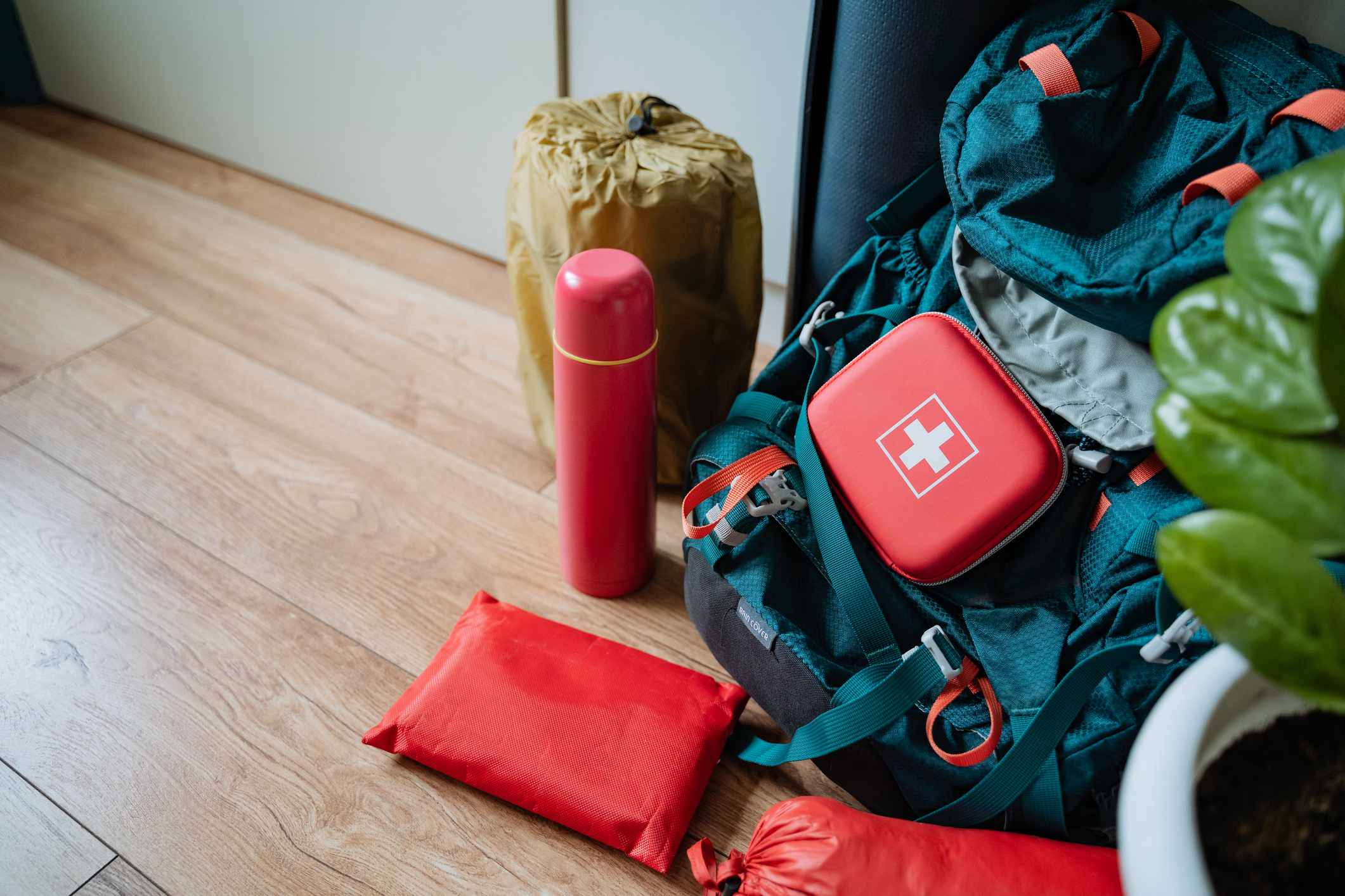 A designated first aid kit is currently placed on the floor right next to a backpack, creating a convenient location for accessing medical supplies if needed during an emergency situation