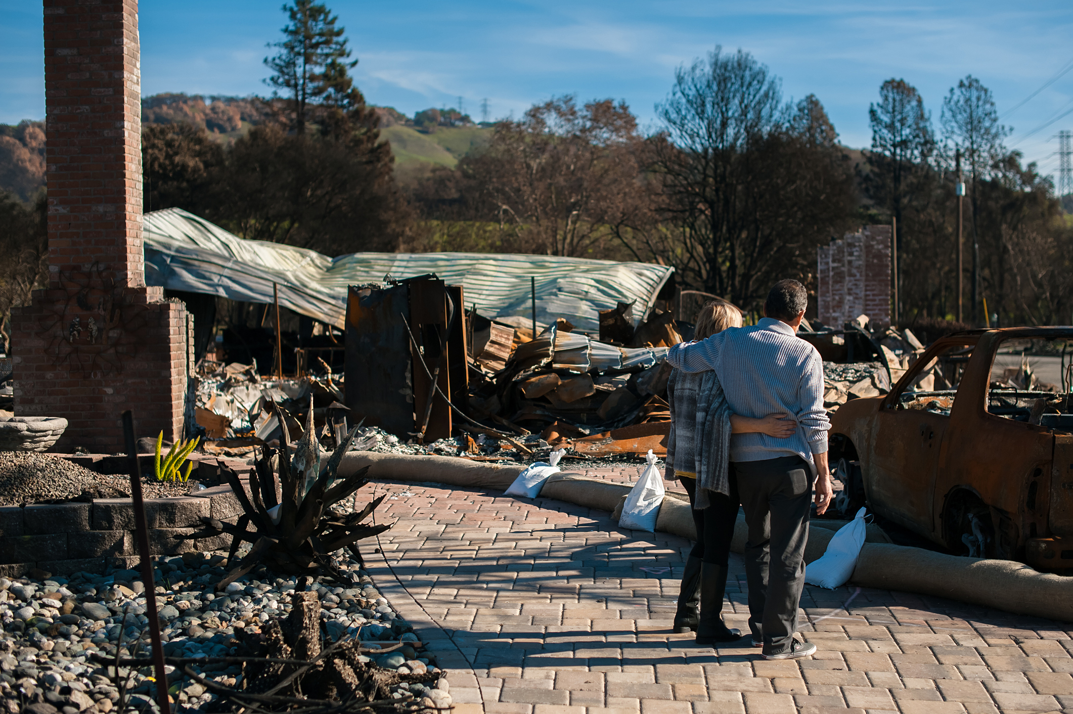 Man and his wife owners, checking burned and ruined house and yard after fire