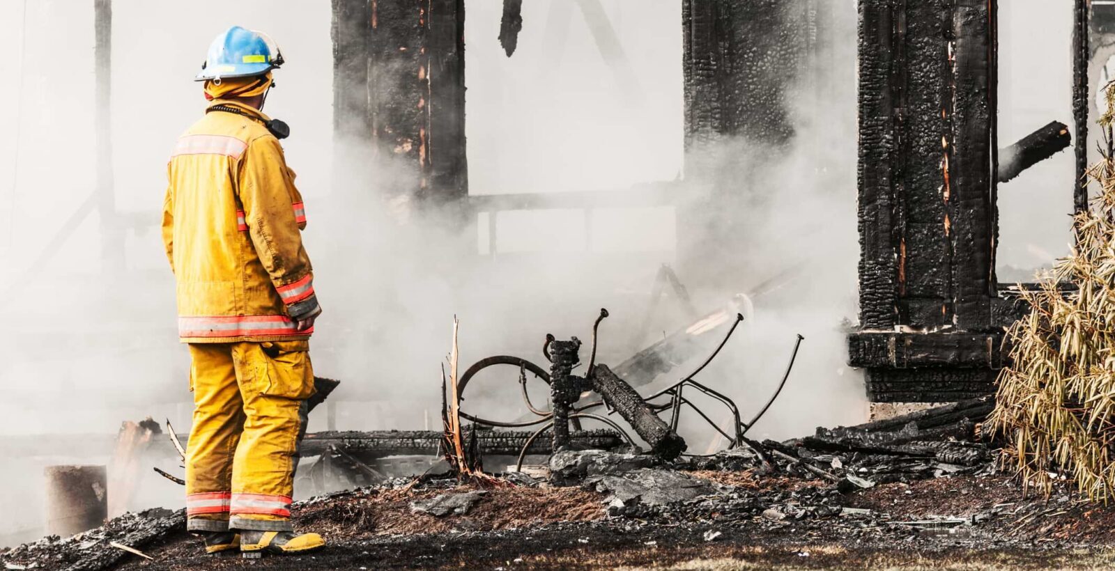 firefighter in front of a fire damaged home