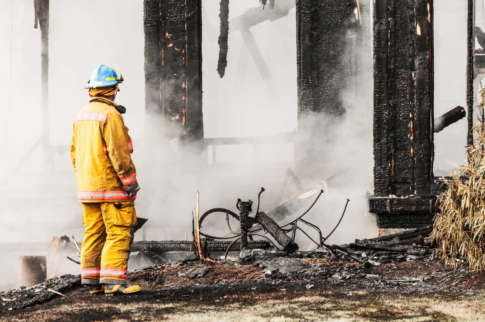 firefighter in front of a fire damaged home