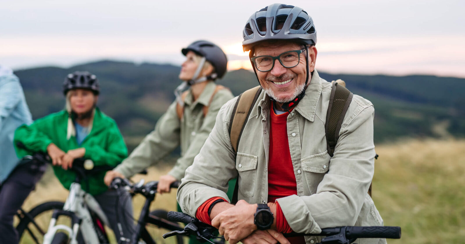 Older man posing with cyclist friends on a bike trail