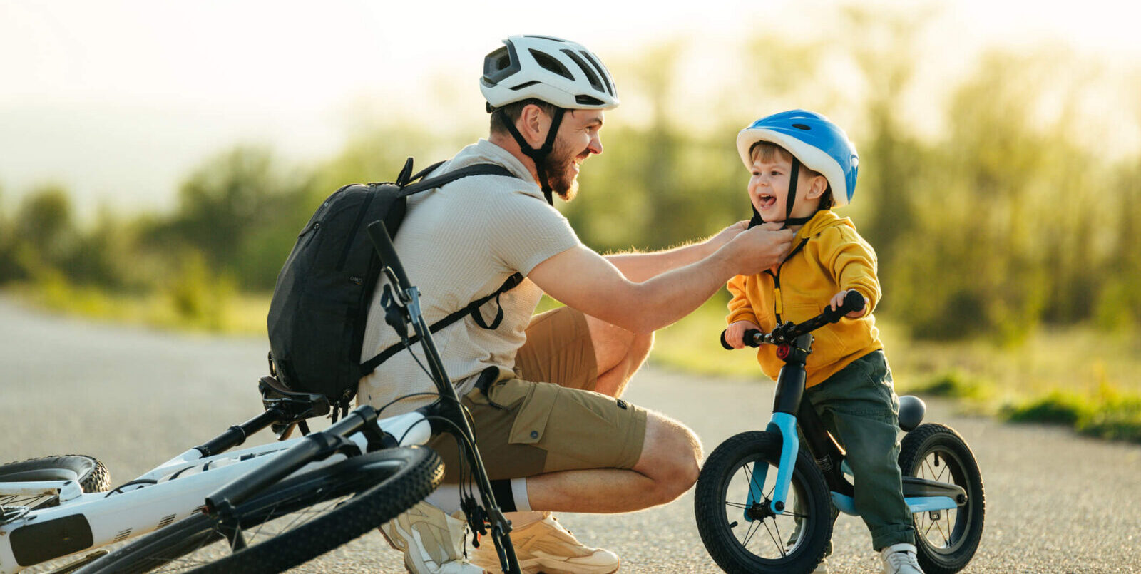 parent and very young child riding bikes on an empty road